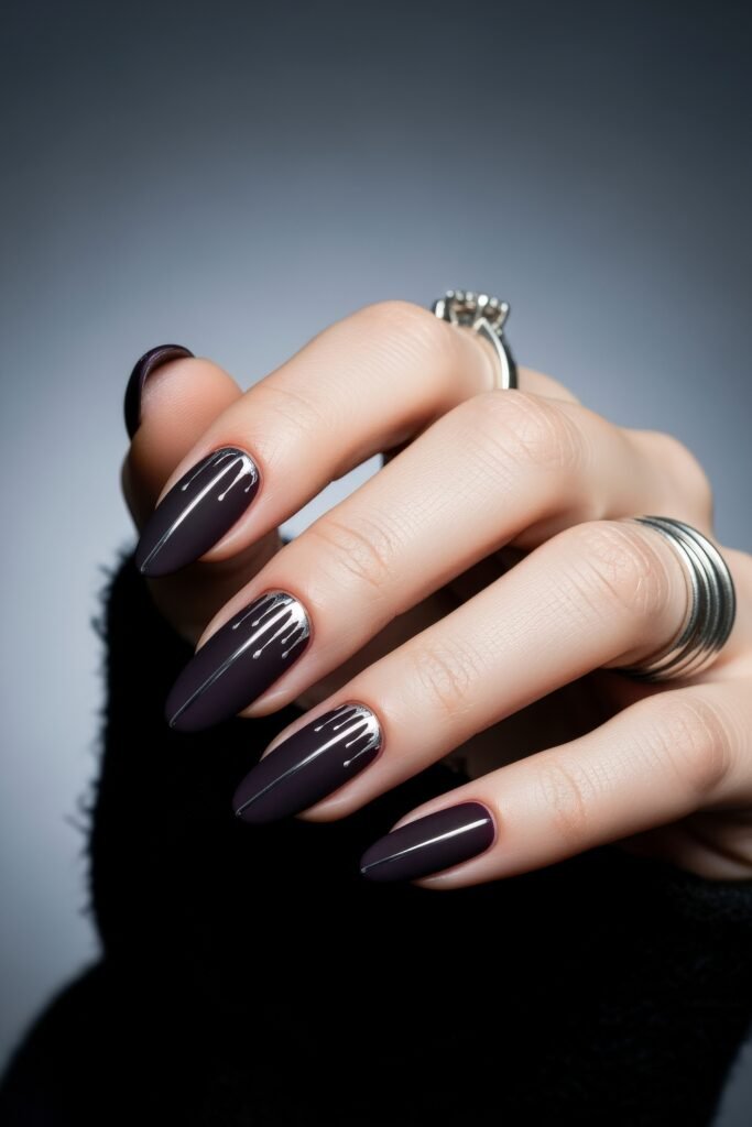 Almond nails in a deep matte plum shade, detailed with metallic silver drips from the cuticle line, offering a dramatic and modern winter nails design.