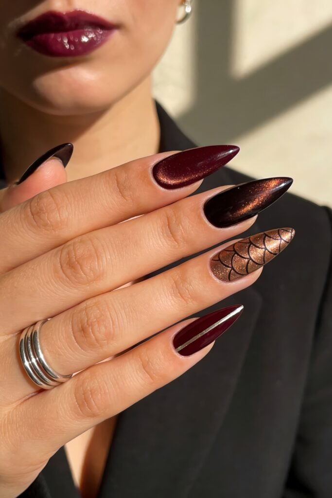 Fire Nails That Look Expensive and Feel Effortless 18 Stiletto nails in deep burgundy and black chrome with a bronze scale-pattern accent and slim metallic stripe