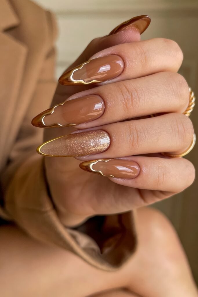Long almond-shaped caramel Goddess Nails featuring thick, wavy molten gold borders and a shimmering gold glitter accent nail
