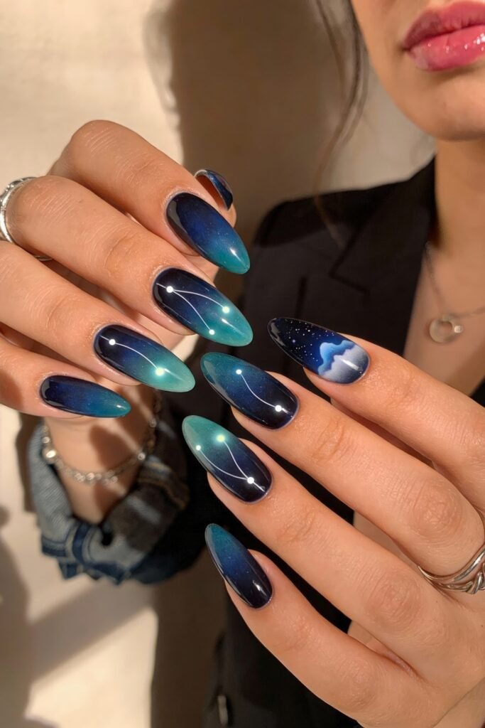 Coordinated hands featuring ombre avatar nails in navy and teal, decorated with constellations, soft gradient skies, and a stylized moonlit cloud scene for a dreamy cosmic atmosphere.