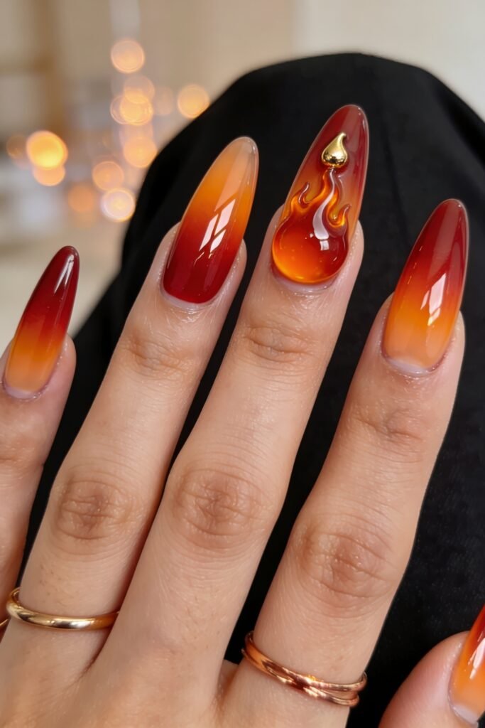 Fire Nails That Look Expensive and Feel Effortless 21 Long almond Fire Nails in red-to-amber ombré with a raised flame accent and small gold charm