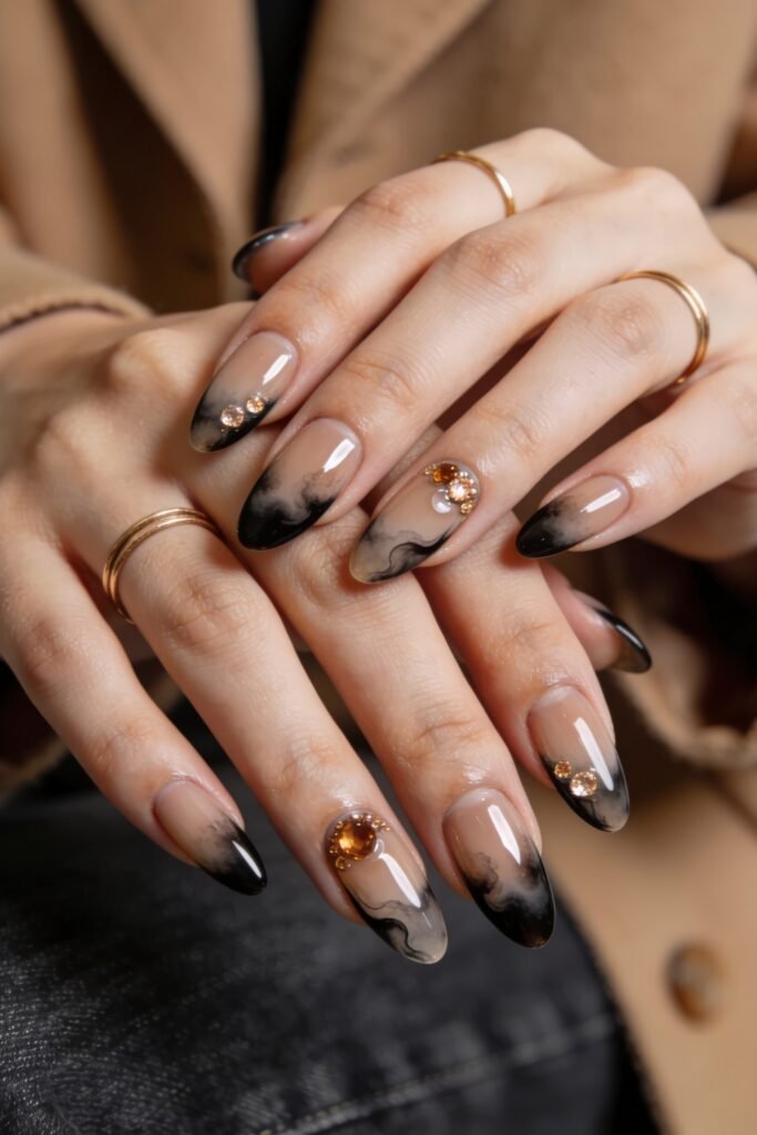 Fire Nails That Look Expensive and Feel Effortless 23 Nude almond nails with smoky black French tips and amber rhinestone clusters, hands stacked with gold rings