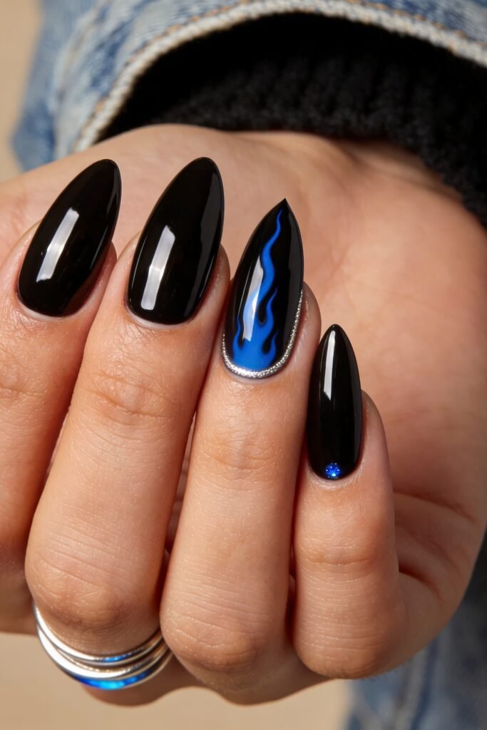 Fire Nails That Look Expensive and Feel Effortless 28 Close-up of glossy black nails with a blue flame accent nail and tiny blue gem detail