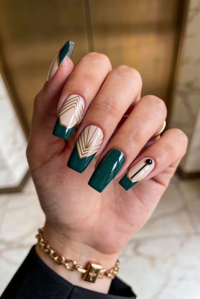 Dark emerald green and nude square nails featuring bold gold Art Deco geometric lines and a black stud.