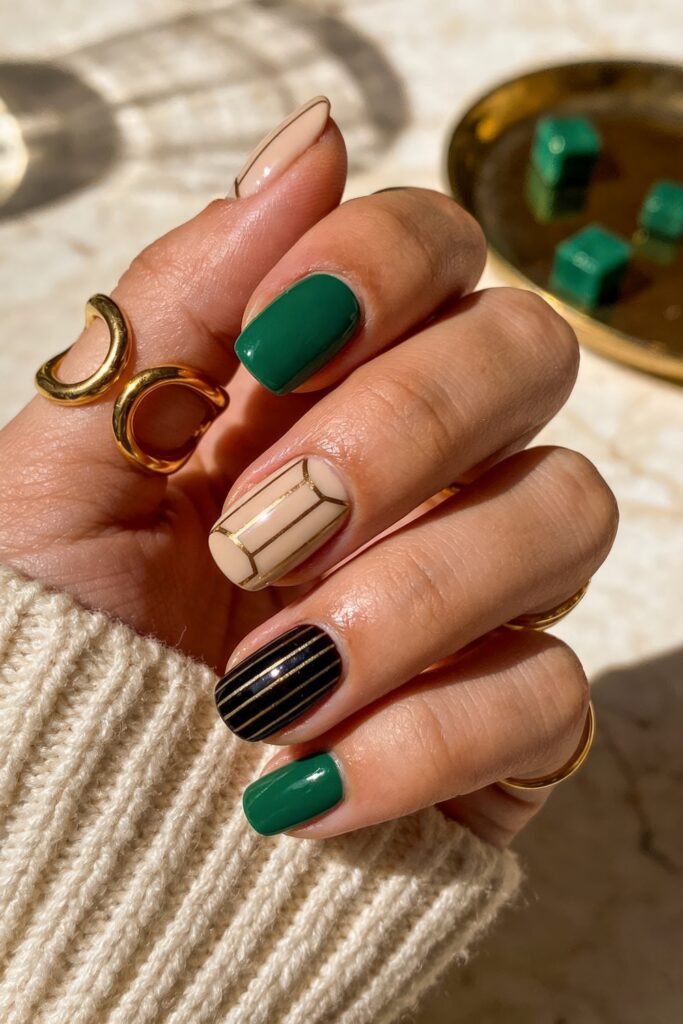 Close up of a hand with dark green and tan geometric goddess nails featuring gold line accents and black stripes.