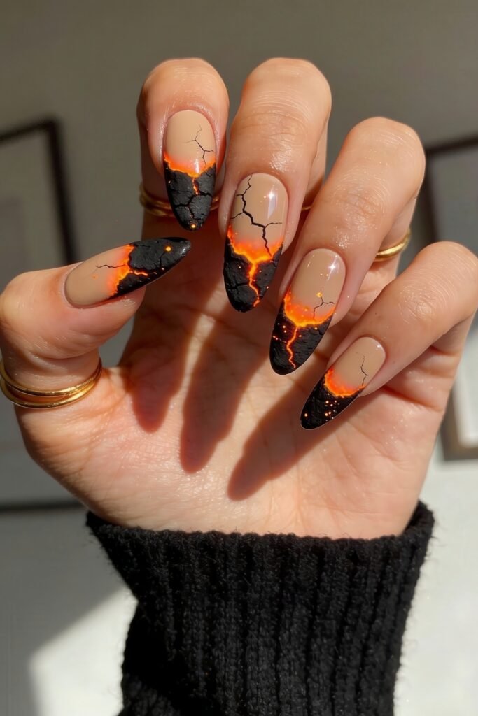 Fire Nails That Look Expensive and Feel Effortless 7 Fire Nails lava-crack design on nude almond nails with black tips and glowing orange fissures