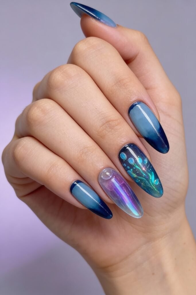 Sleek almond avatar nails in a deep blue gradient with subtle iridescent and holographic details, including a glowing handprint motif and a water droplet accent, inspired by Avatar's ocean world.