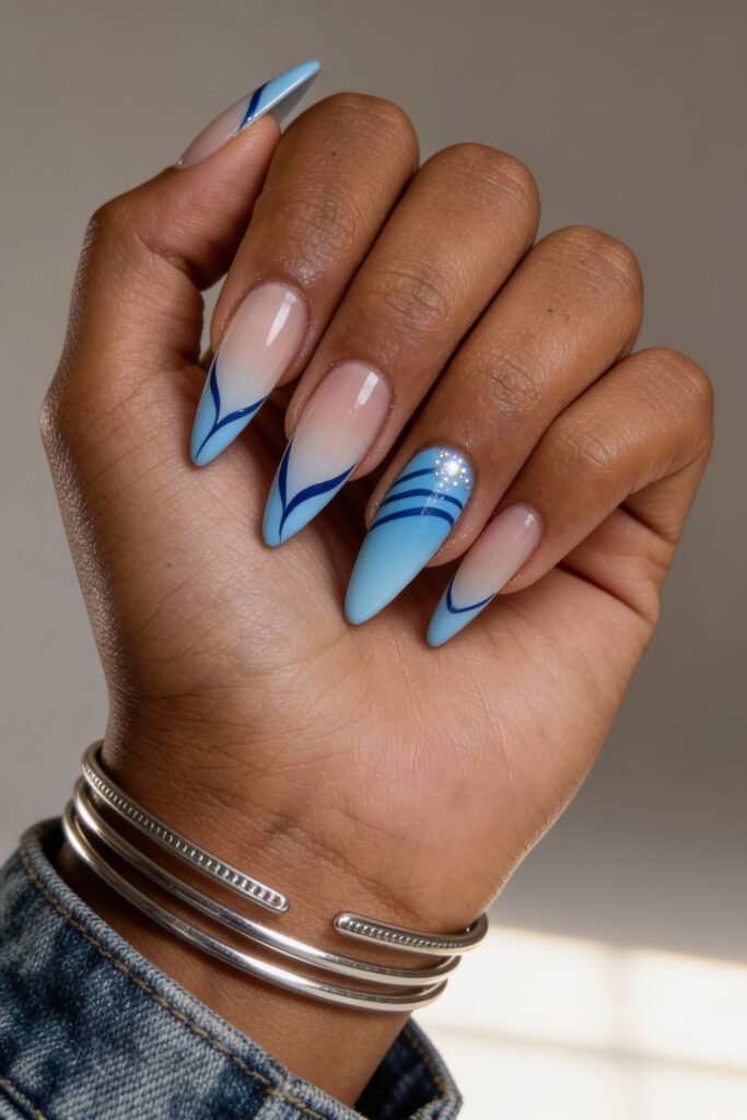 Almond-shaped nails blending nude and baby blue, featuring clean wave-like blue striping and dotted accents, channeling a crisp aquatic vibe.