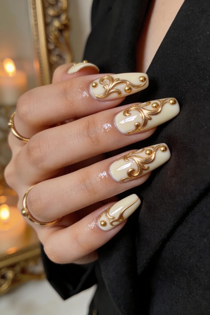 Long coffin-shaped off-white Goddess Nails featuring elaborate 3D golden filigree swirls and delicate gold bead embellishments