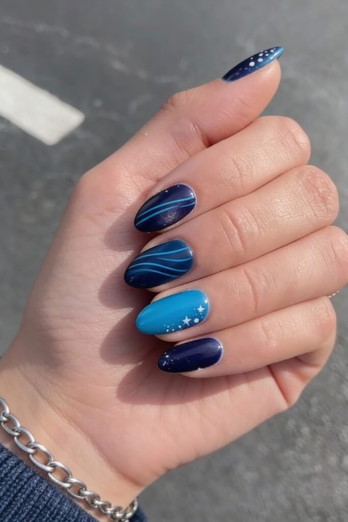 Elegant avatar nails in varying shades of blue with vertical and curved lines, white dots, and a star accent on a bold turquoise nail, inspired by ocean movement and celestial themes.