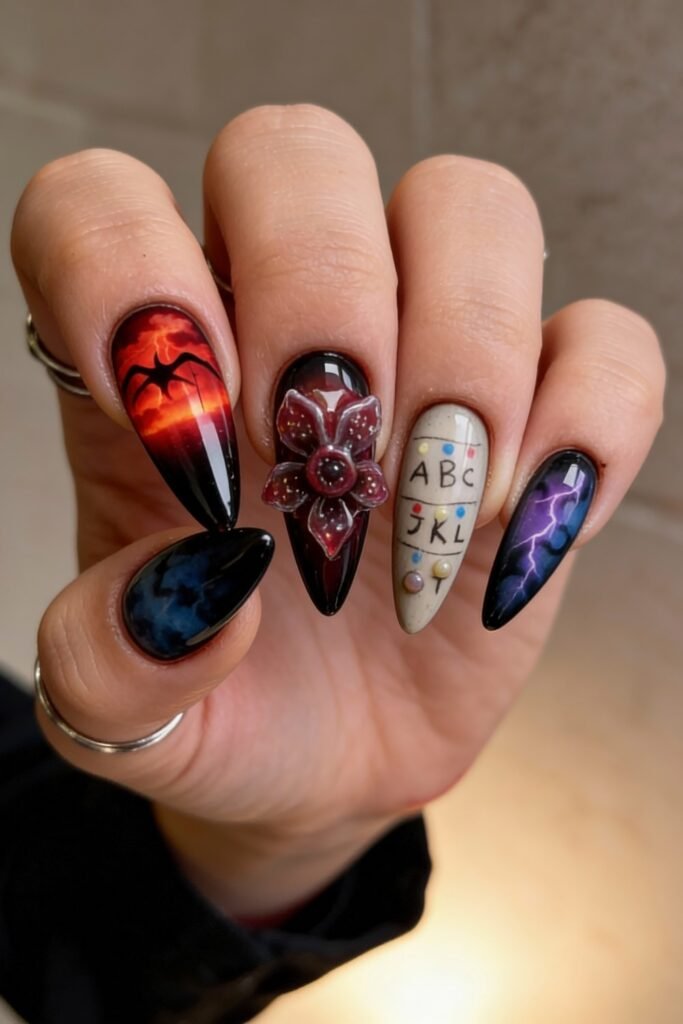 Stiletto nails with a vivid Stranger Things design, including a glowing red sky with a shadow monster, a 3D Demogorgon flower, the alphabet wall with bulbs, and purple lightning on a dark gradient.