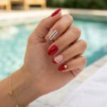Brown And Red Nails That Make Every Look Richer Poolside close up of almond nails with glossy red polish a striped accent nail and a tiny gold shell charm for a chic summer manicure