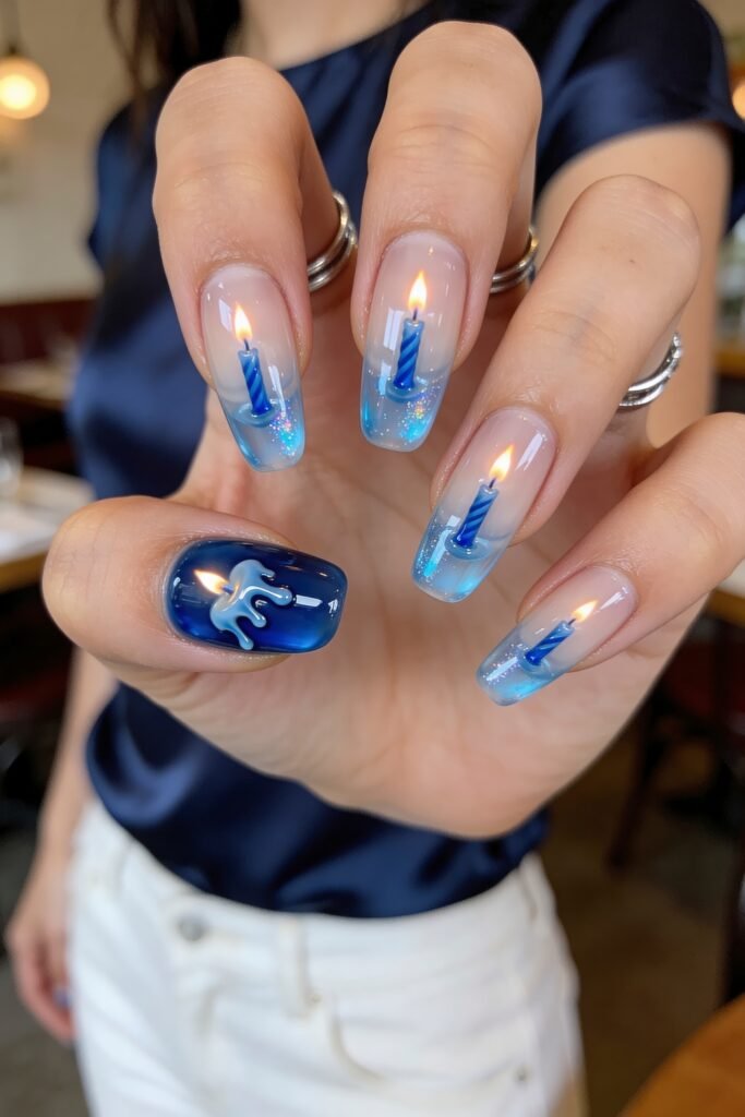 Close-up of a hand with translucent blue ombré nails designed like lit blue birthday candles, with a melted wax accent on the thumb