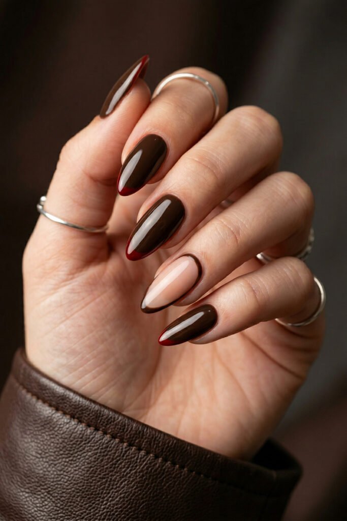 Brown And Red Nails That Make Every Look Richer 21 Close up of almond nails with glossy chocolate polish burgundy French tips and one nude accent nail with a brown outline