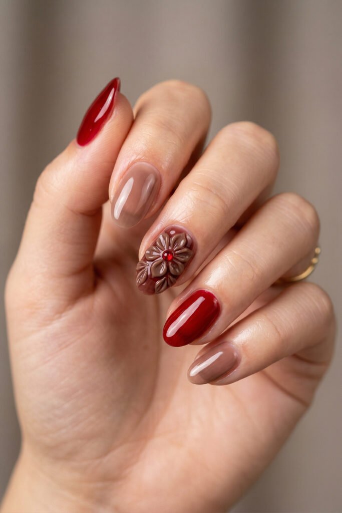 Brown And Red Nails That Make Every Look Richer 23 Hand with glossy red and taupe nails featuring a raised brown flower design with a red gem center against a soft neutral background