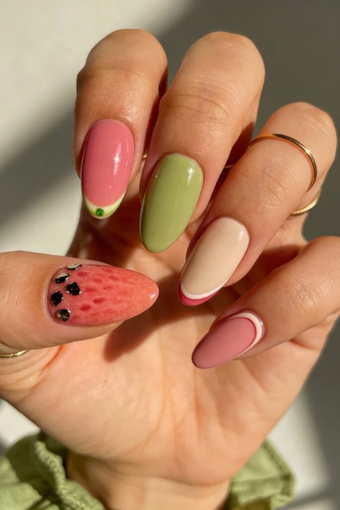 Summer Birthday Nails That Feel Fresh and Fun 26 Hand with soft pink and green nails featuring watermelon seed art a pale green accent and curved abstract line details