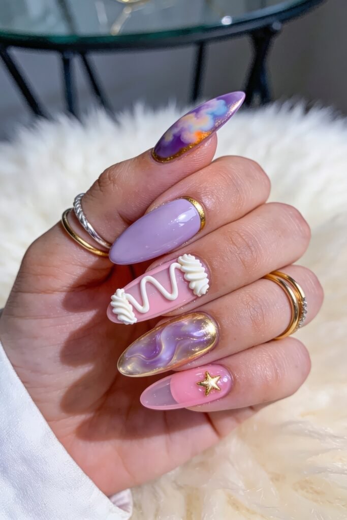 Gold Birthday Nails That Feel So Chic 9 Close-up of long almond nails in lavender, pink, and gold with cloudy marbled designs, a 3D white swirl accent, a gold star charm, and glossy pastel finishes