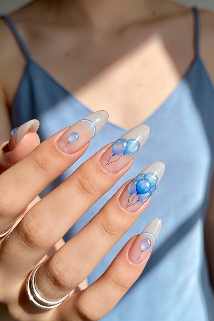 Close-up of almond-shaped sheer white nails with delicate blue balloon designs and pale blue French tip accents