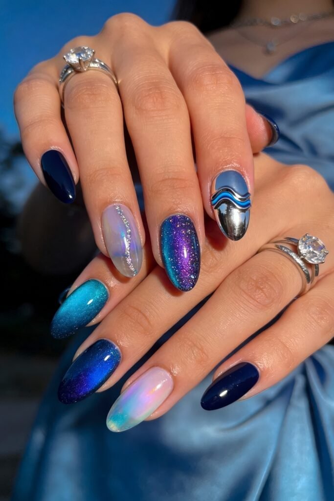 Summer Birthday Nails That Feel Fresh and Fun 10 Two hands with galaxy inspired almond nails featuring navy blue shimmer chrome and iridescent ombre designs against a blue satin outfit