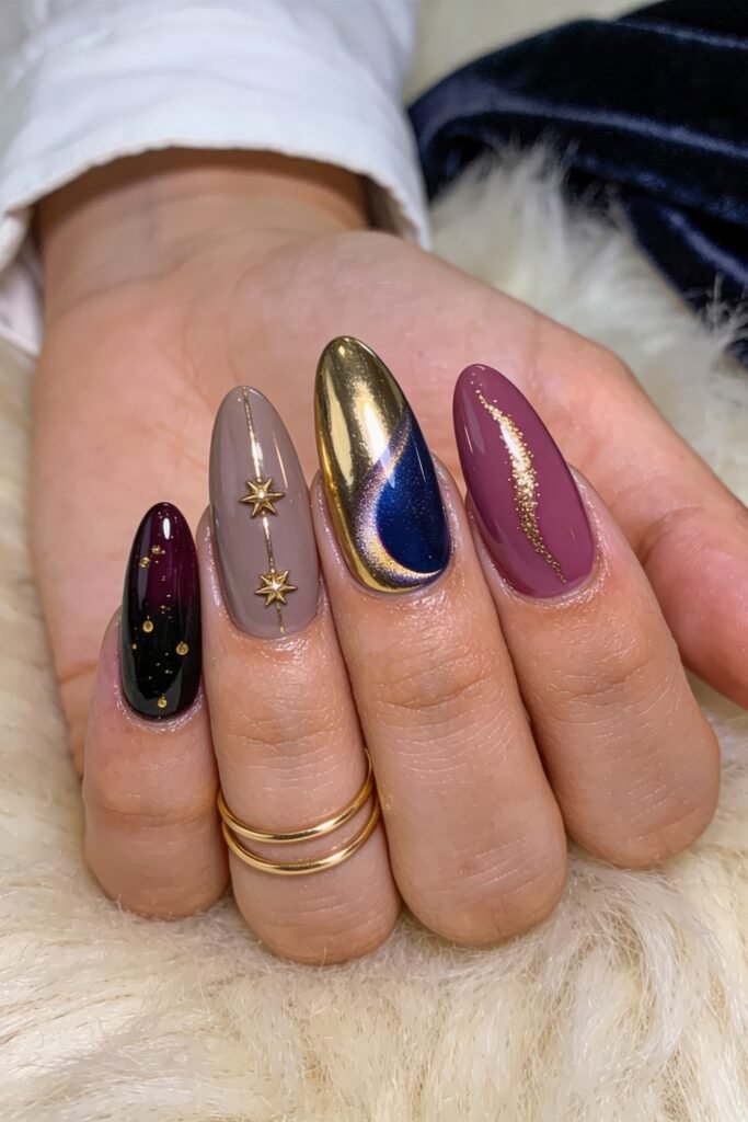 Gold Birthday Nails That Feel So Chic 11 Close-up of almond-shaped nails in burgundy, taupe, blue, and mauve with gold celestial accents, including star charms, gold flecks, and a chrome gold-and-blue swirl