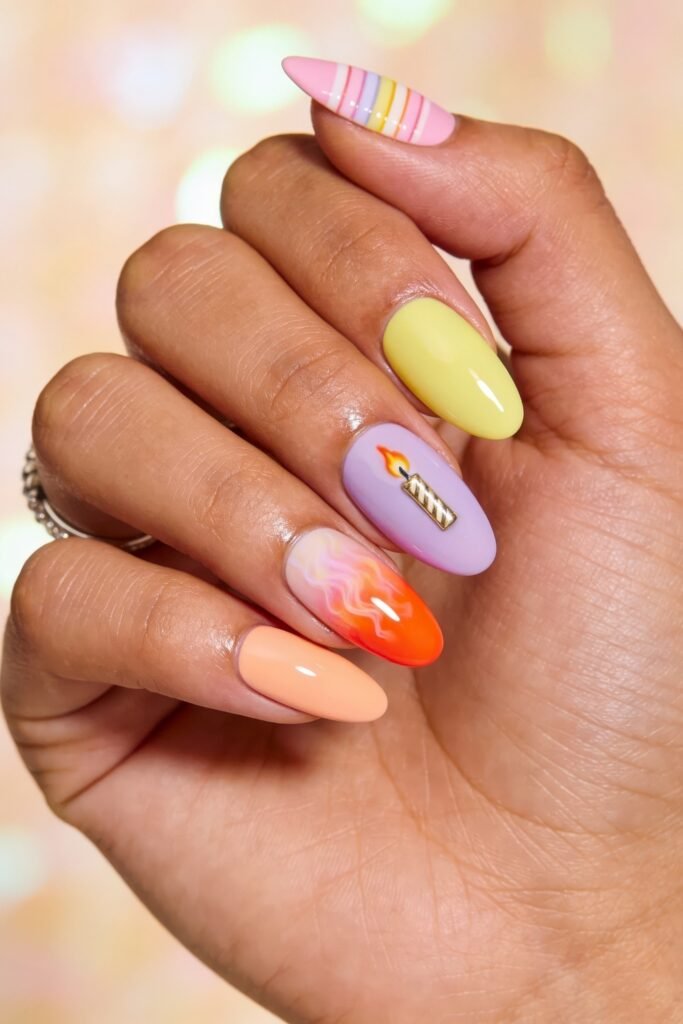 Summer Birthday Nails That Feel Fresh and Fun 13 Hand with pastel almond nails featuring yellow peach lavender and pink shades with striped tips a candle accent and a smoky orange swirl design