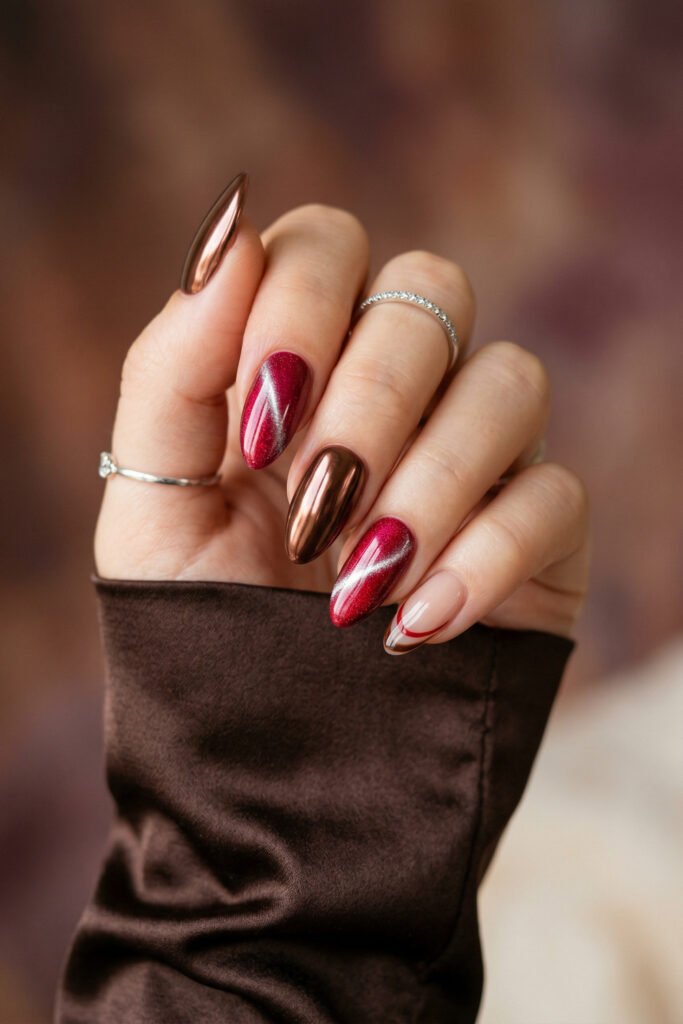 Brown And Red Nails That Make Every Look Richer 15 Hand with red cat eye and bronze chrome almond nails featuring a nude accent nail with curved red and brown lines