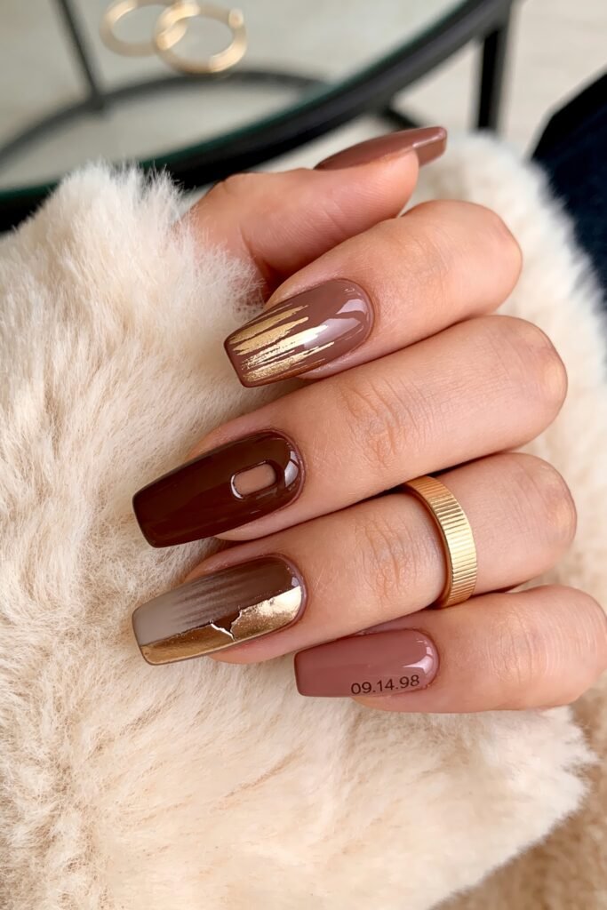 Gold Birthday Nails That Feel So Chic 17 Close-up of brown coffin nails with glossy and matte finishes, featuring gold brushstrokes, a negative-space accent, an abstract taupe and gold design, and the date 09.14.98