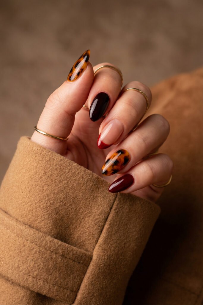 Elegant fall red nails in an almond shape with deep wine polish, a slim red French tip, and glossy tortoiseshell accents.
