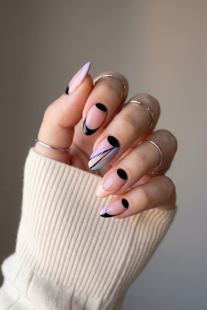 Chic edgy spring nails with black French tips, pastel lilac and blue striping, and glossy almond shapes on a soft nude base.
