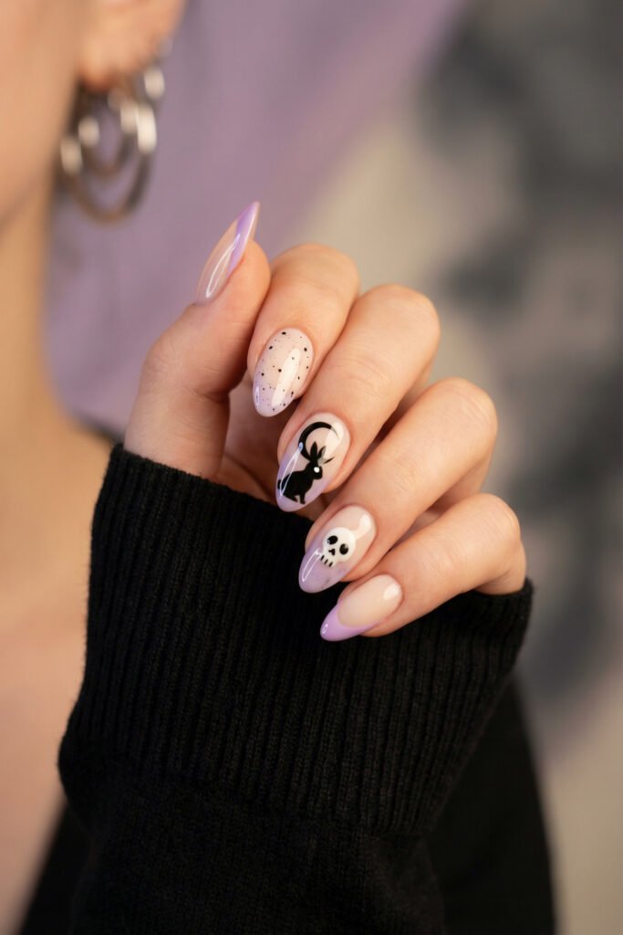 Pale lilac almond nails with black speckles, a bunny silhouette, and a skull accent for a cute spooky spring goth nails manicure with soft ombré tips.
