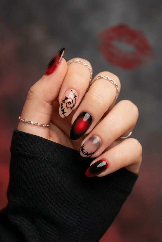 Black and Red Nails for a Bold, Polished Look 23 Hand with silver chain rings displaying black and red aura nails with barbed wire art and a small red gem accent