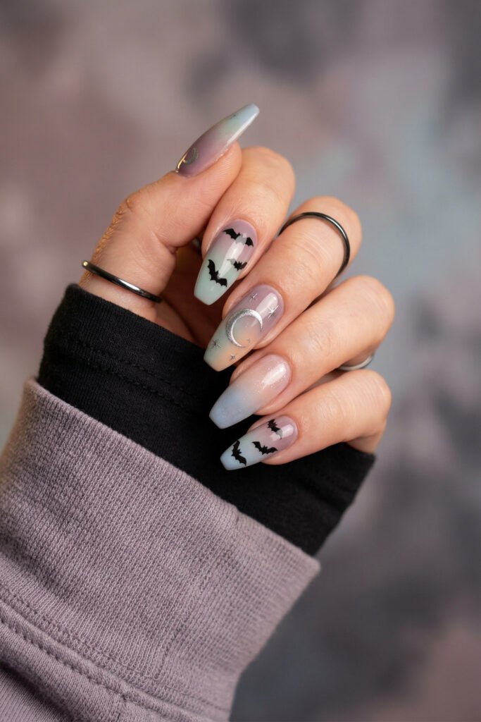Lavender and mint coffin nails with black bat art, a crescent moon, stars, and a soft shimmer accent in a whimsical spring goth nails design.
