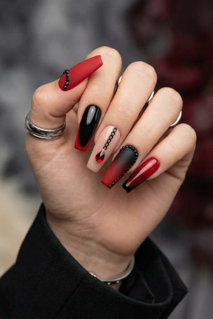 Black and Red Nails for a Bold, Polished Look 26 Hand with silver rings showing red black and nude coffin nails with black bead accents a chain design and a red gem drop