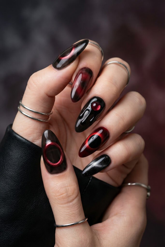 Black and Red Nails for a Bold, Polished Look 4 Hand with silver rings displaying black and burgundy almond nails with smoky gradients a glossy drip accent and a subtle glitter nail