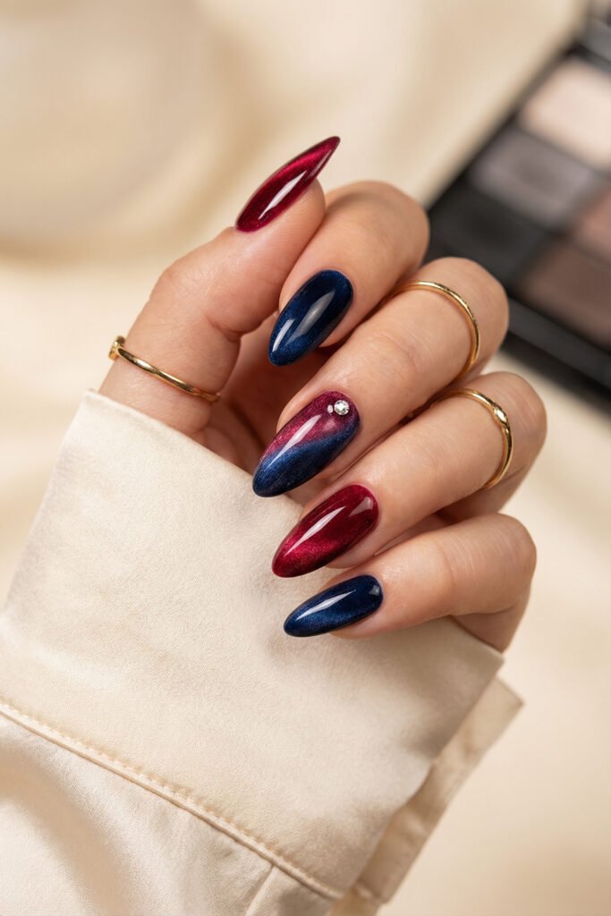 Shimmery almond blue and red nails with magnetic velvet finish, navy and wine tones, gradient accent nail, and rhinestone detail
