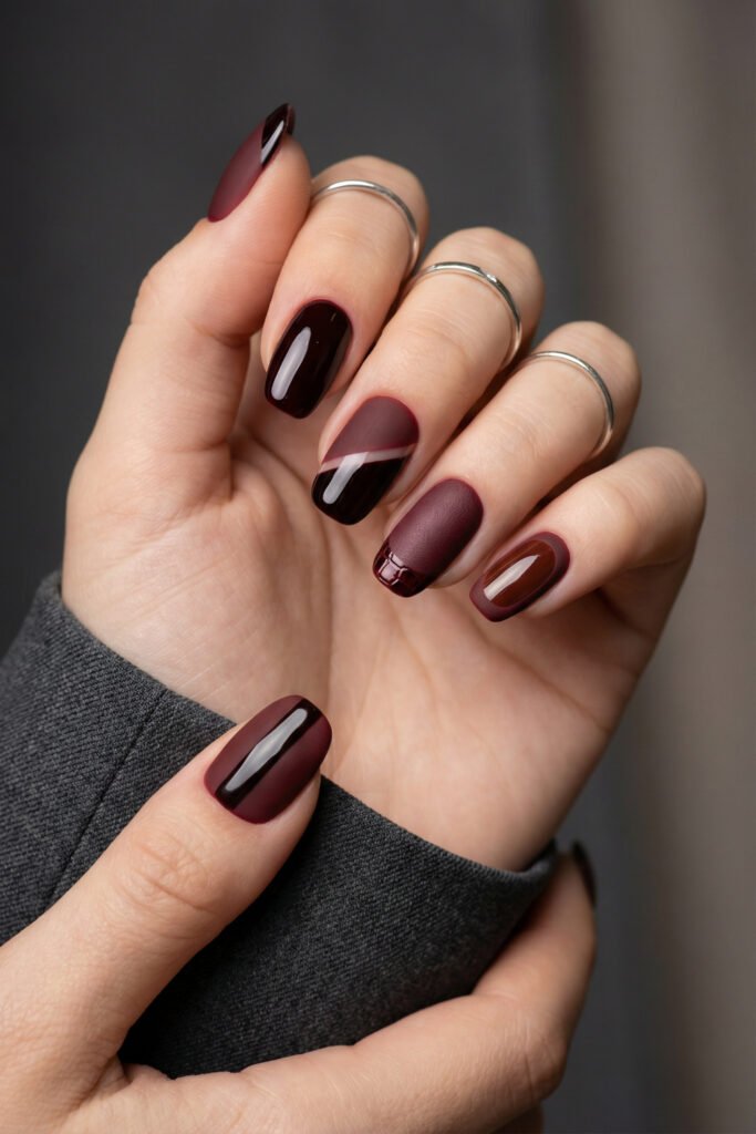 Deep fall red nails in square shapes with matte and glossy wine finishes, color-blocked accents, and a modern rich-girl manicure.
