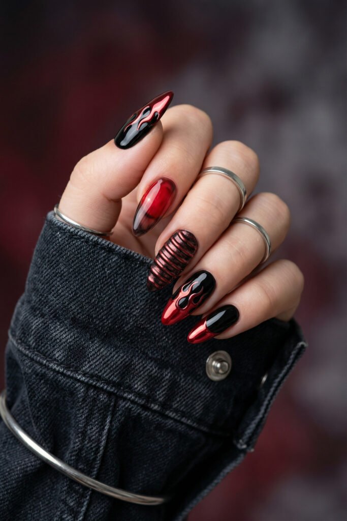 Black and Red Nails for a Bold, Polished Look 11 Hand with silver rings showing black and chrome red almond nails featuring flame art a ribbed accent and smoky red ombre