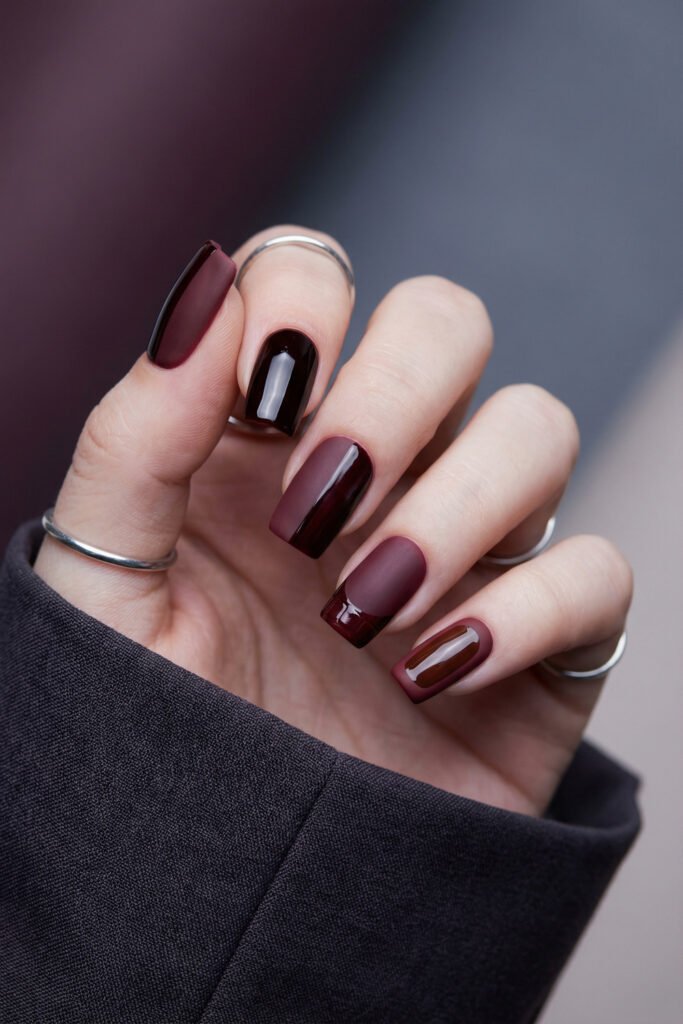 Square fall red nails with dark wine tones, matte-gloss contrast, sleek color blocking, and glossy French-inspired accent details.
