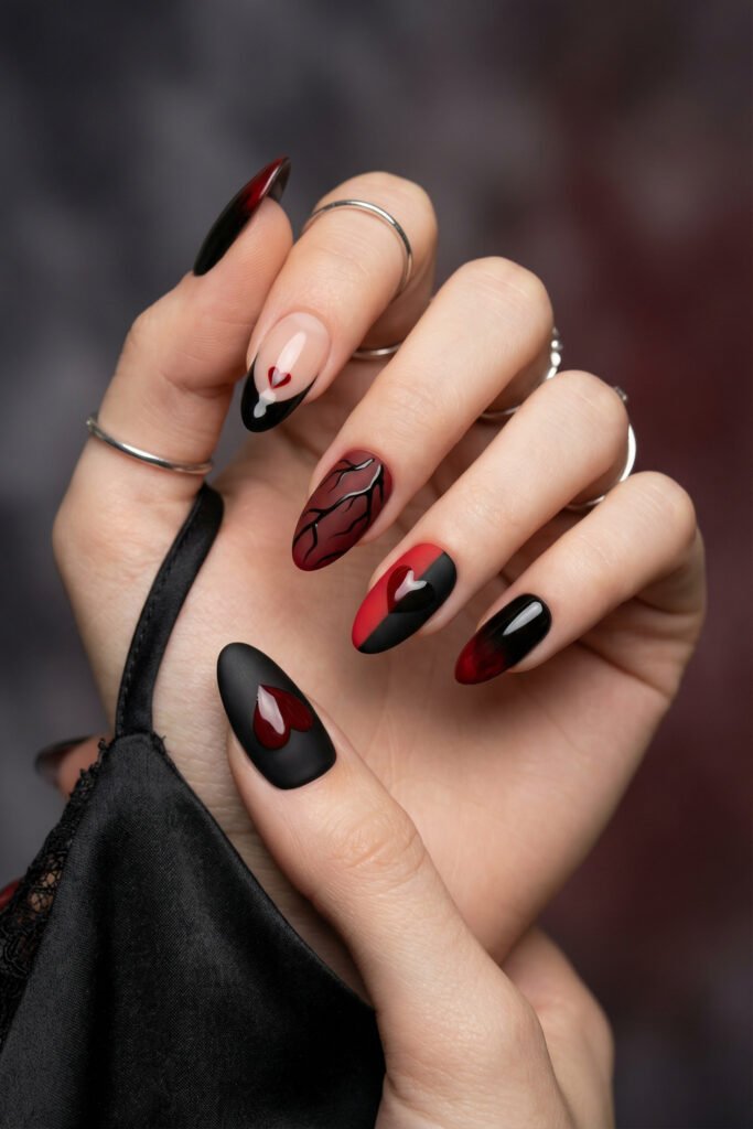 Black and Red Nails for a Bold, Polished Look 16 Hand with silver rings showing matte and glossy black red and nude almond nails featuring heart accents and a vein inspired design