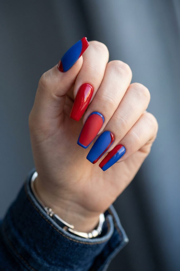 Matte and glossy blue and red nails in a long coffin shape featuring color-blocked panels, curved side detailing, and a bold modern finish
