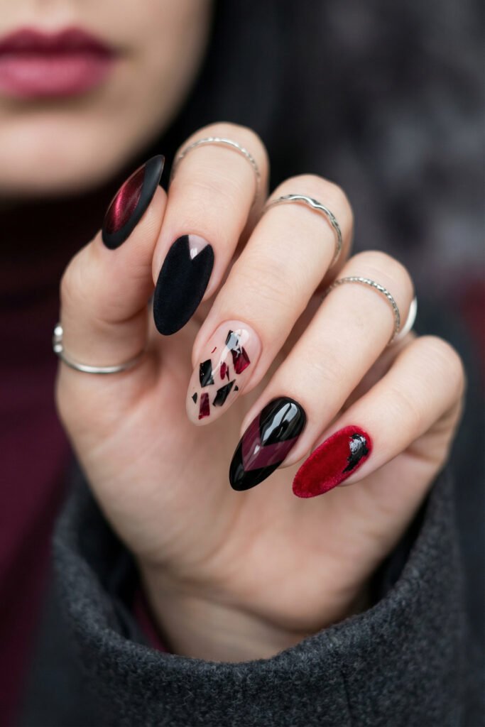 Black and Red Nails for a Bold, Polished Look 18 Hand with silver rings and dramatic almond nails featuring velvet red black crystal shards and a textured ruby accent